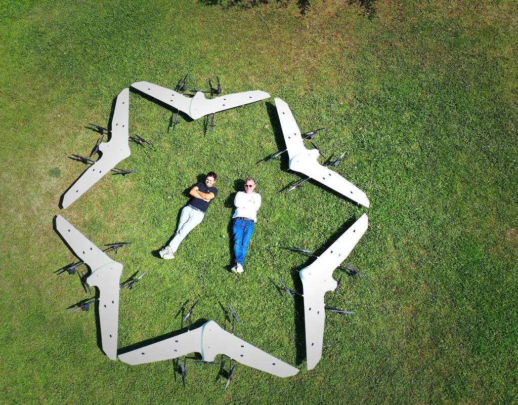 Six Nimbus aircraft laid out in a hexagon on the grass, seen from above, with two people lying in the middle